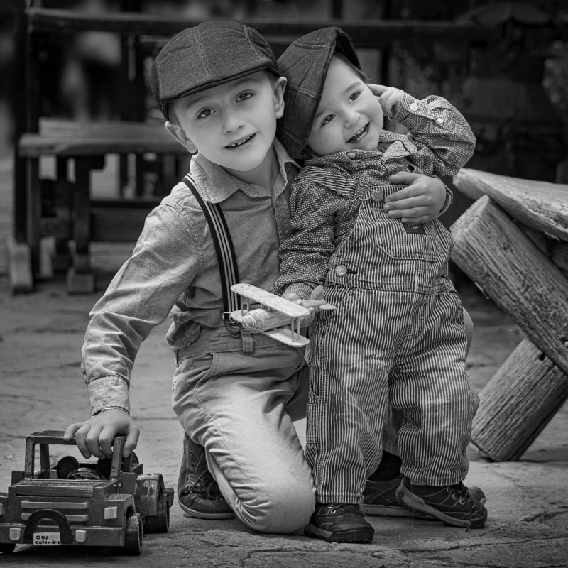 Jongen met jonger kind in de armen spelend met een truck